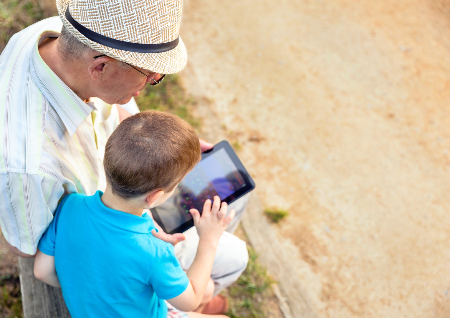 An elderly man and his grandchild playing on a tablet home care